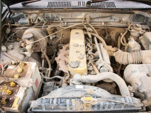 A close-up of a dirty engine bay, relevant to installing used engines. Check the maintenance history!