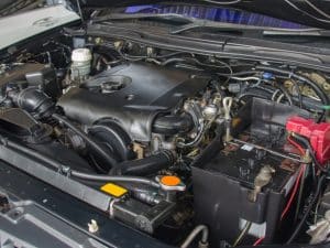 Close-up of a car engine bay, showing components relevant to installing used engines, like the battery and coolant reservoir.